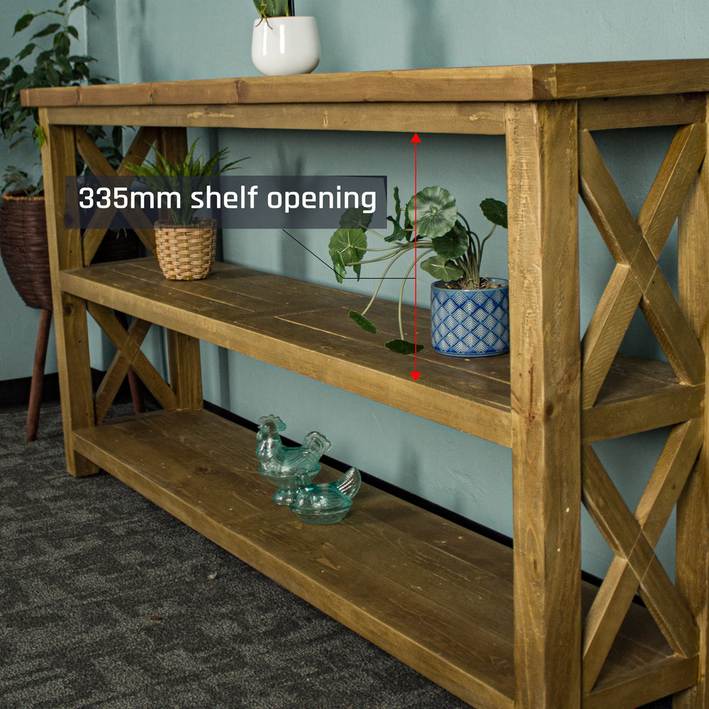 A side-on view of the Ventura Recycled Pine Large Hall Table. There are two equidistant potted plants on the middle shelf and two blue glass ornaments on the bottom shelf.