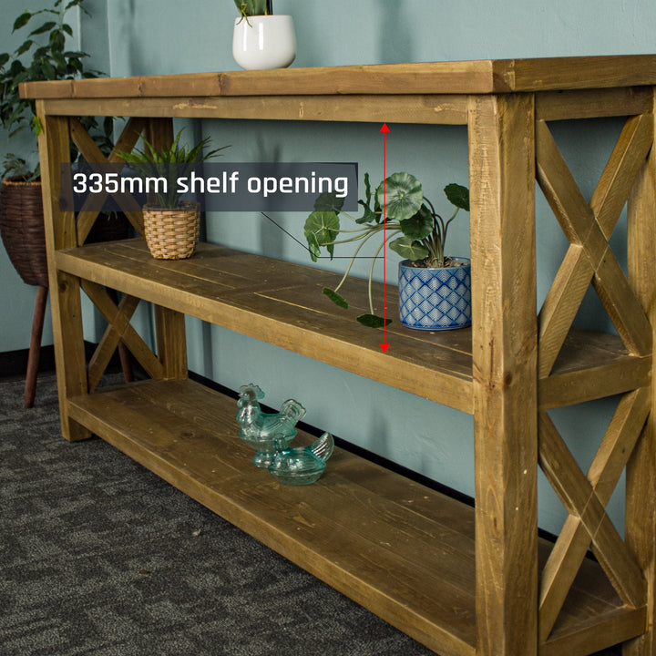 A side-on view of the Ventura Recycled Pine Large Hall Table. There are two equidistant potted plants on the middle shelf and two blue glass ornaments on the bottom shelf.