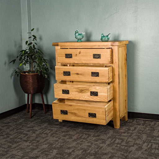 The front of the Yes Four Drawer Oak Tallboy with its drawers open. There are two blue glass ornaments on top and a free standing potted plant next to the unit.