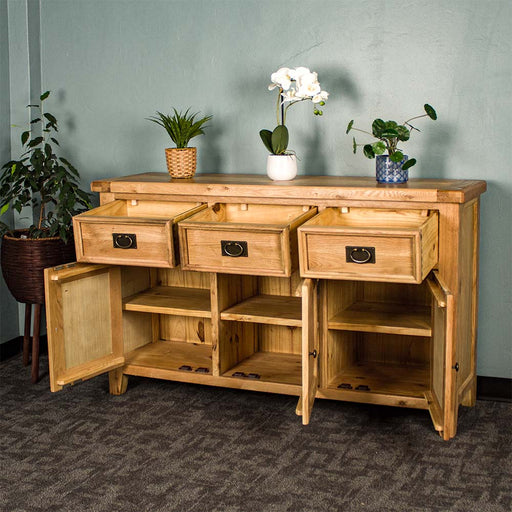 The front of the Yes 3 Door 3 Drawer Oak Buffet with its doors and drawers open. There are three potted plants on top and a free standing potted plant next to the sideboard.