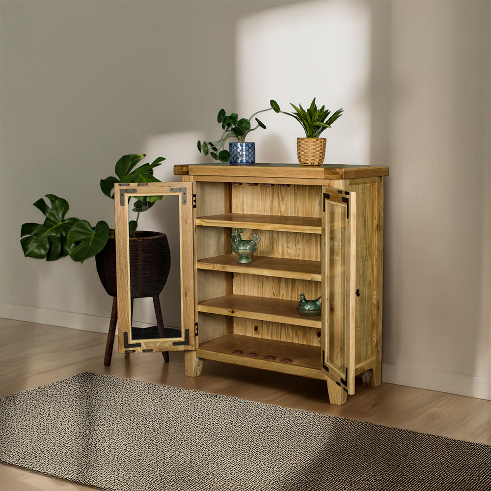 The front of the Yes Oak Display Cabinet with its doors open. There are two blue glass ornaments on the middle shelves. There are two potted plants on top and a tall, free standing potted plant next to the cabinet.