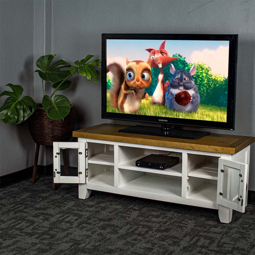 The front of the Felixstowe 2 Door Entertainment Unit with its doors open. There is a large TV on top, with a DVD player on the top shelf in the middle. There is a free standing potted plant next to the unit.