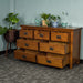 The front of the Montreal 7 Drawer Pine Lowboy with its drawers open. There are two blue glass ornaments on top with two potted plants in between. There is a free standing potted plant next to the lowboy.