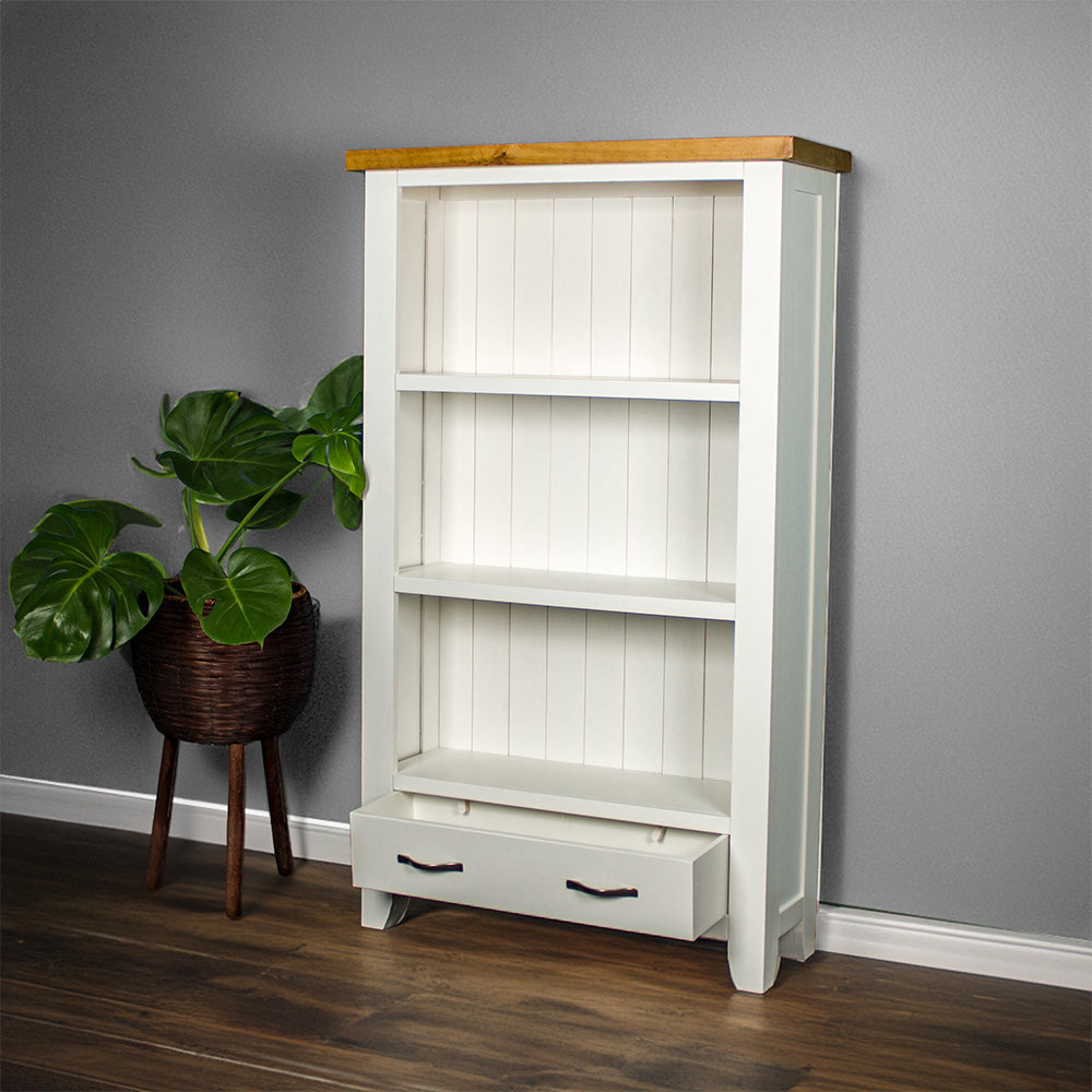 The front of the Felixstowe Pine Bookcase with its drawers open and a potted plant next to it.