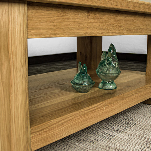 A view of the shelf under the Camden Oak Coffee Table. There are two blue glass ornaments in the shape of chickens.