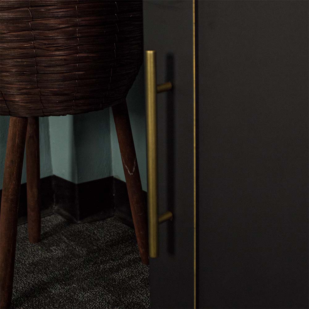 A close up of the gold coloured metal handle on the Cascais Small Black Cupboard.