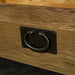 A close up of the hanging-style metal drawer handle on the Vancouver Value Oak Entertainment Unit.