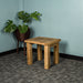 The larger of the two Amstel Oak Nesting Tables. There is a tall free standing potted plant behind it.