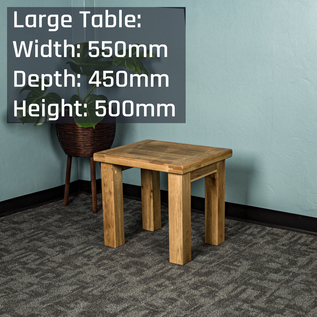 The larger of the two Amstel Oak Nesting Tables. There is a tall free standing potted plant behind it.