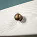 A close up of the brushed brass coloured handle on the drawer of the Loire Two-Tone Medium Oak Buffet.
