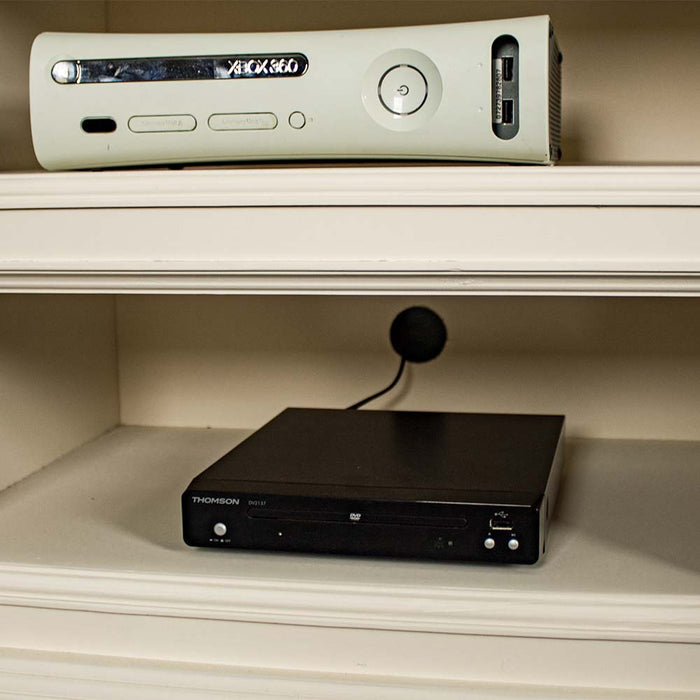 A closer view of the cable hole on the back of the Biarritz Entertainment Unit. There is a game console and a DVD player on the top and bottom shelves.