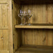 A view of the larger shelf on the Cairns Recycled Pine Buffet. There are three wine glasses on the shelf.