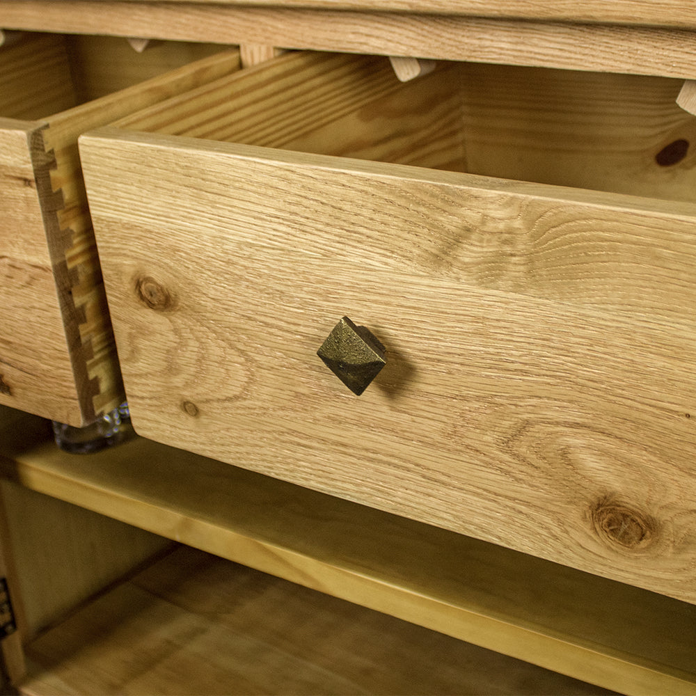 A close up of the brushed metal diamond shaped handle on the Maximus Small Oak Buffet.