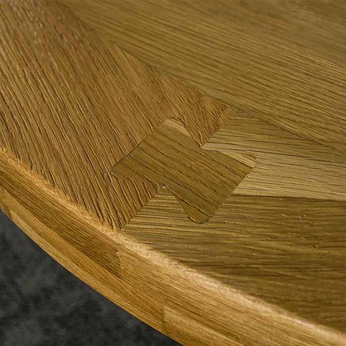 Close up of the top of the Amstel Round Oak Dining Table, showing the wood grain and dovetail joinery.