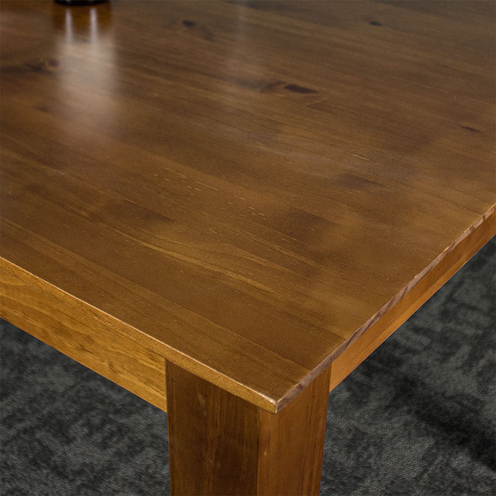 A close up of the top of the Hamilton Rimu Stained Dining Table (1500mm), showing the wood grain and smooth rimu finish.