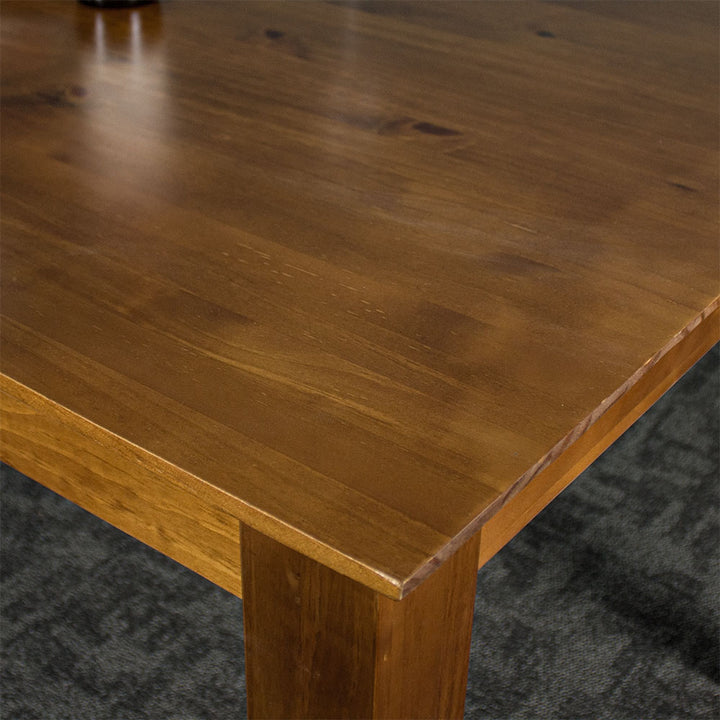 A close up of the top of the Hamilton Rimu Stained Dining Table (1500mm), showing the wood grain and smooth rimu finish.