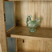 A view of the shelf on the Vienna Oak Glass DIsplay Cabinet. There is a blue glass ornament in the shape of a chicken on display.