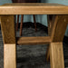 The smaller Amstel Oak Nesting Table from the side, with cross legs and a support bar in the middle.