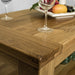 A close up of the top of the Camden Oak Coffee Table, showing the wood grain and colour. There are two wine glasses and a fruit platter that can be seen on top.