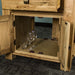 An overall view of the lower shelf of the Danube Compact Granite Top Oak Kitchen Island, which has two sets of glasses and wine glasses next to each other.