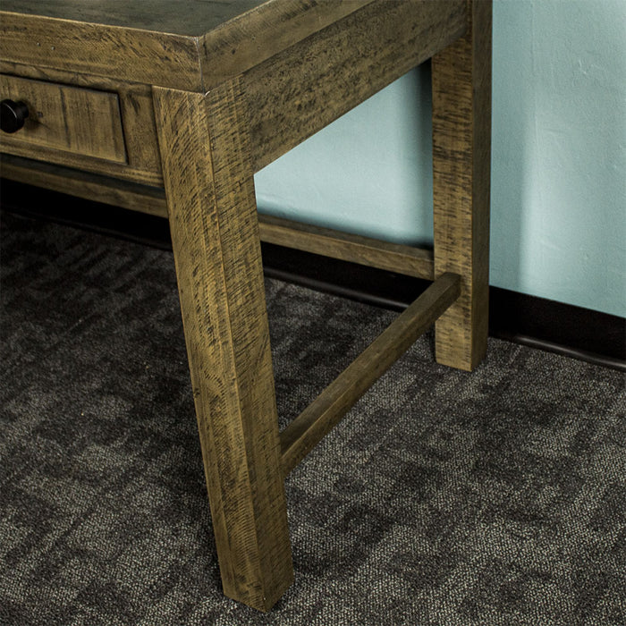The edge of the Stonemill Recycled Pine Desk, showing the support bars connecting the legs along the side and back.