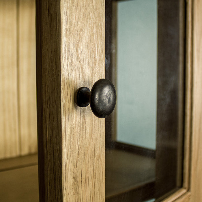 A close up of the round door handle on the Yes 2 Door 4 Drawer Glass Display Cabinet.
