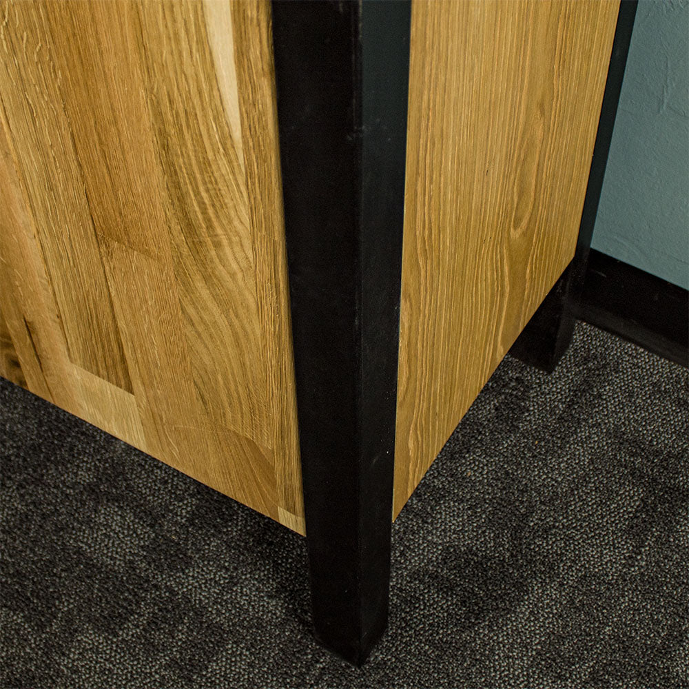 A close up of the black metal leg on the Golden Gate Three Door Oak Buffet