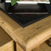 A close up of the top of the Danube Compact Granite Top Oak Kitchen Island, showing the wood grains and the shiny granite top.