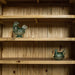 An overall view of the shelves on the Yes Oak Display Cabinet. There are two blue glass ornaments in the shape of a chicken on the two middle shelves.