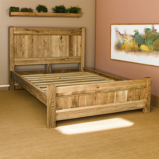 An overall view of the Amalfi Oak Queen Bed Frame in a bedroom. There is a painting on the wall and plants on a free hanging shelf above the bed.