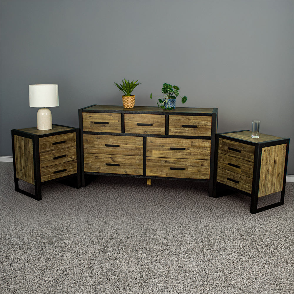 The Victor 7 Drawer Lowboy with two Victor 3 Drawer Bedside Cabinets on either side. There are two potted plants on top of the lowboy and a lamp on the left bedside, and a glass of water on the right bedside.