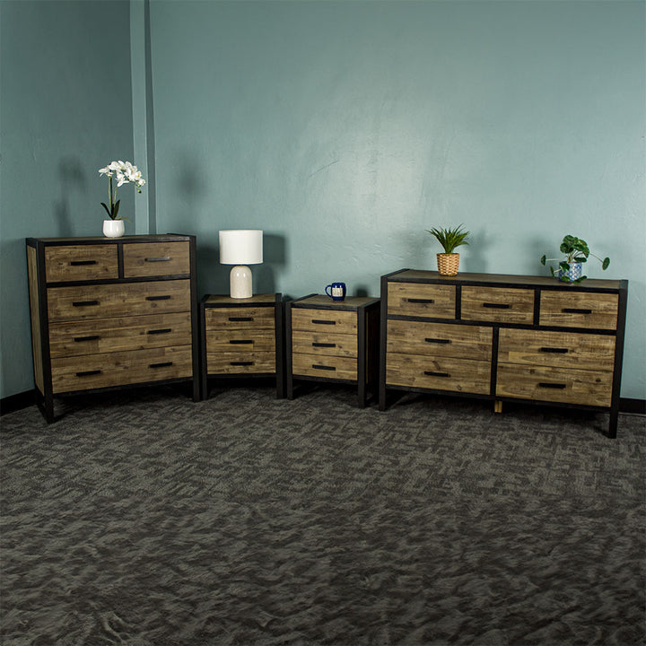 From left to right: Victor 5 Drawer Tallboy, two Victor 3 Drawer Bedside Cabinets and a Victor 7 Drawer Lowboy. There is a small pot of flowers on the tallboy, a lamp on the left bedside, a blue coffee mug on the right bedside, and two potted plants on the lowboy.