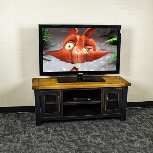 The front of the Cascais Oak-Top TV Unit. There is a large TV on top and a DVD player on the top shelf in the middle.