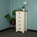 The front of the Alton 5 Drawer Lingerie Chest. There is a free standing potted plant next to it. There are two blue glass ornaments and a pot of white flowers on top.