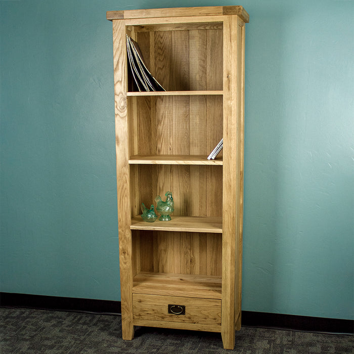 The front of the Yes Tall Oak Bookcase. There are a stack of vinyl records, two dvd cases and two glass blue ornaments on the shelves.