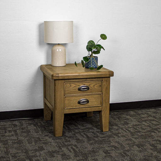 The front of the Houston Oak Lamp Table. There is a lamp and a potted plant on top.