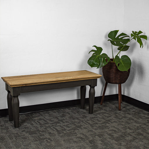 An overall view of the Boston Short Oak Bench. There is a free standing potted plant next to it.