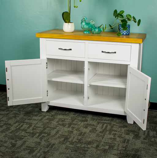 The front of the Felixstowe Small Pine Buffet (White) with its doors open. There are two potted plants with two blue glass ornaments in between them on top of the sideboard.