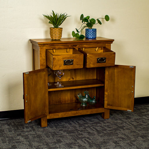 The front of the Montreal Small Pine Buffet with its drawers and doors open. There are two potted plants on top. There are three wine glasses on the top shelf, and two blue glass ornaments on the lower shelf.