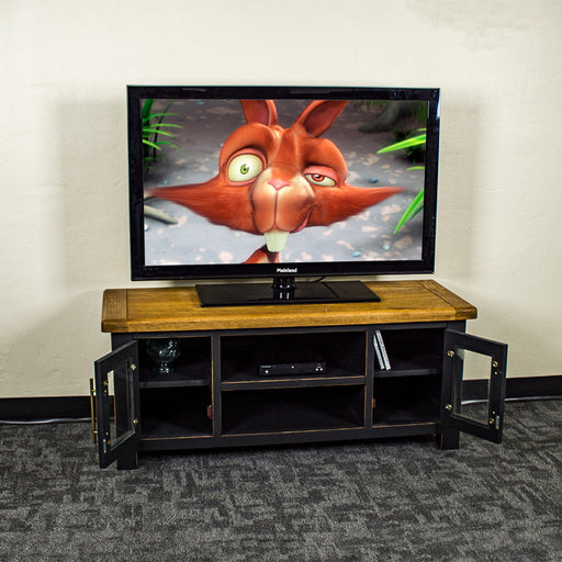 The front of the Cascais Oak-Top TV Unit with its doors open. There is a large TV on top with a DVD player on the top drawer in the middle.