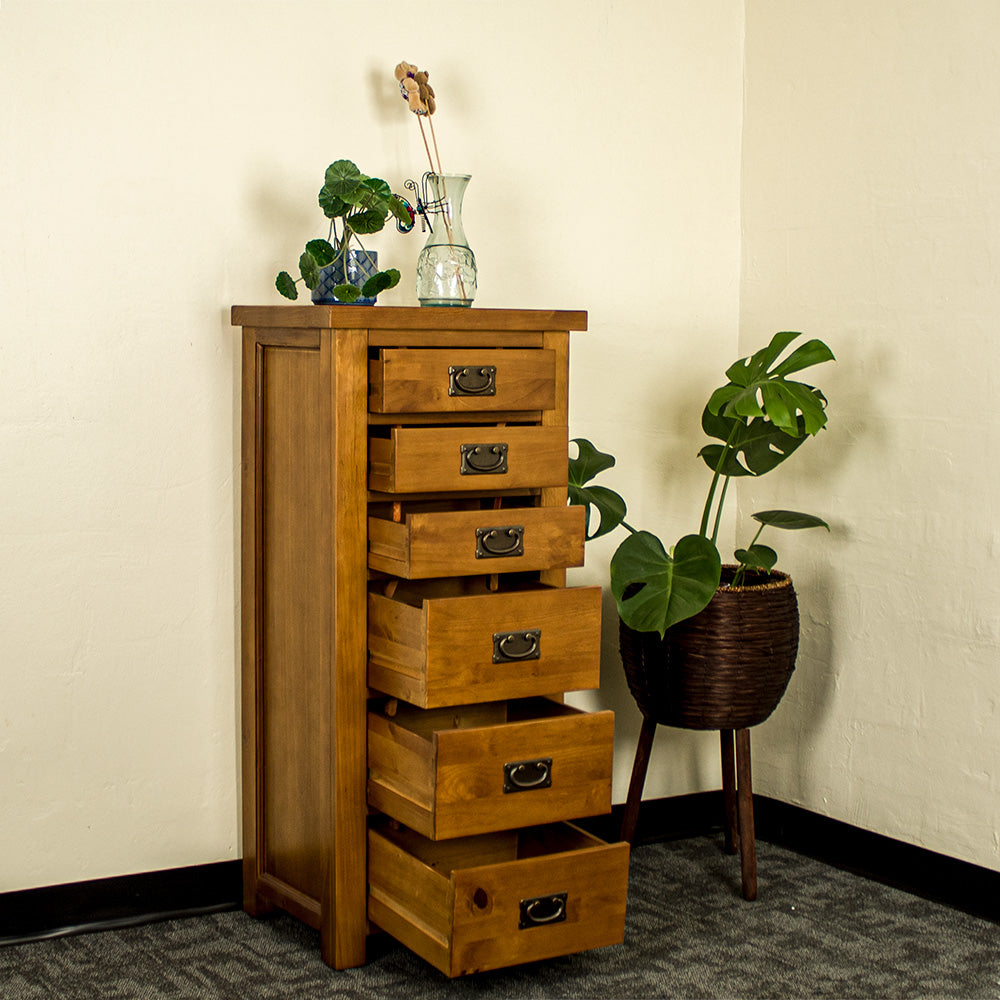 The front of the New Quebec 6 Drawer Lingerie Chest with its drawers open. There is a free standing potted plant next to it and a potted plant on top next to a blue glass vase.