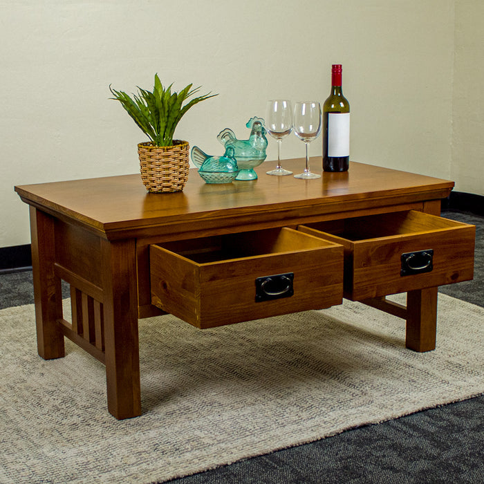 The front of the Montreal Coffee Table with 2 Drawers with its drawers open. There is a potted plant, two blue glass ornaments, two wine glasses and a bottle of wine on top.