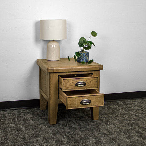 The front of the Houston Oak Lamp Table with its drawers open. There is a lamp and a potted plant on top.