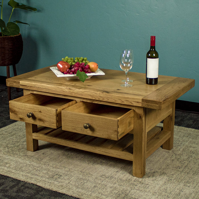 The front of the Farmhouse Coffee Table with its drawers open. There is a fruit platter, two wine glasses and a wine bottle on top.