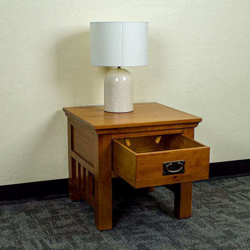 The front of the Montreal Pine Lamp Table, with its drawer open. There is a lamp on top.