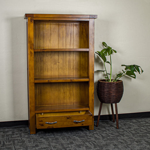 The front of the Monaco Bookcase with its drawers open. There is a free standing potted plant next to it.