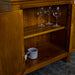 A closer view of the shelving inside the Montreal Compact Pine Buffet. There are three wine glasses on the top shelf and two coffee mugs on the lower shelf.