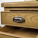 A close up of the brushed silver coloured circular metal handle on the drawers of the Houston Oak Lamp Table