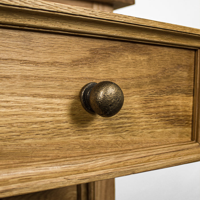 A close up of the brushed brass handle on the Versailles Oak Bedside Cabinet.