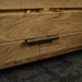 A close up of the brushed brass handle on the drawers of the Camden 2 Drawer White Oak Entertainment Unit.